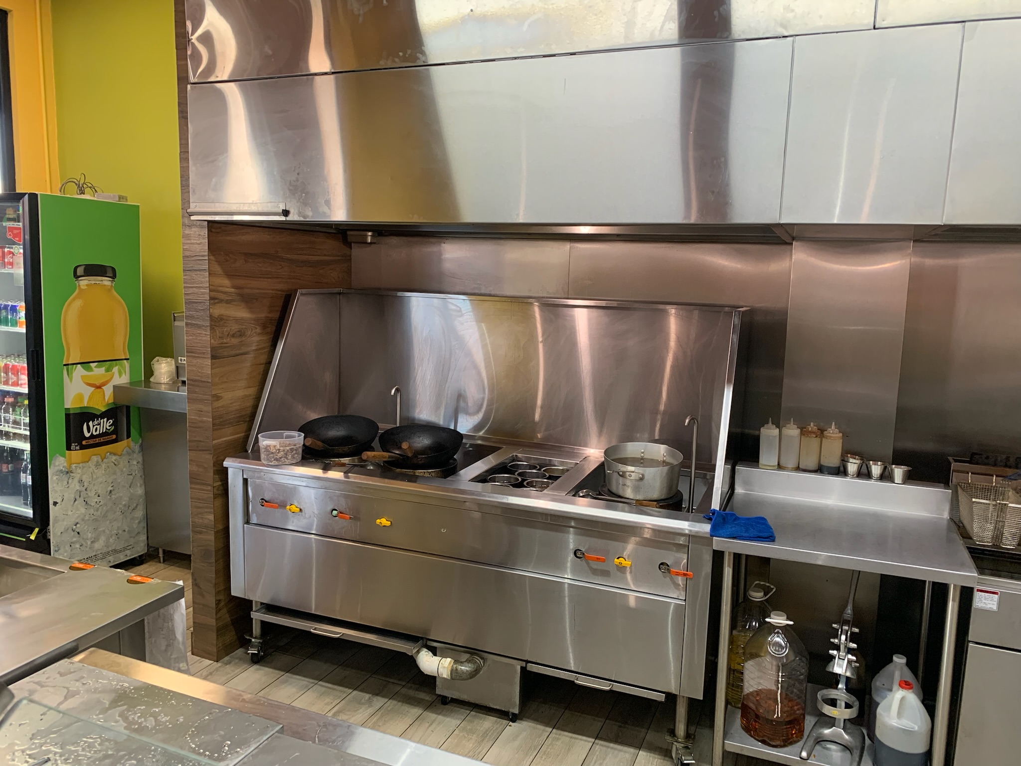 Cocina industrial instalada con woks, plancha y tarja
