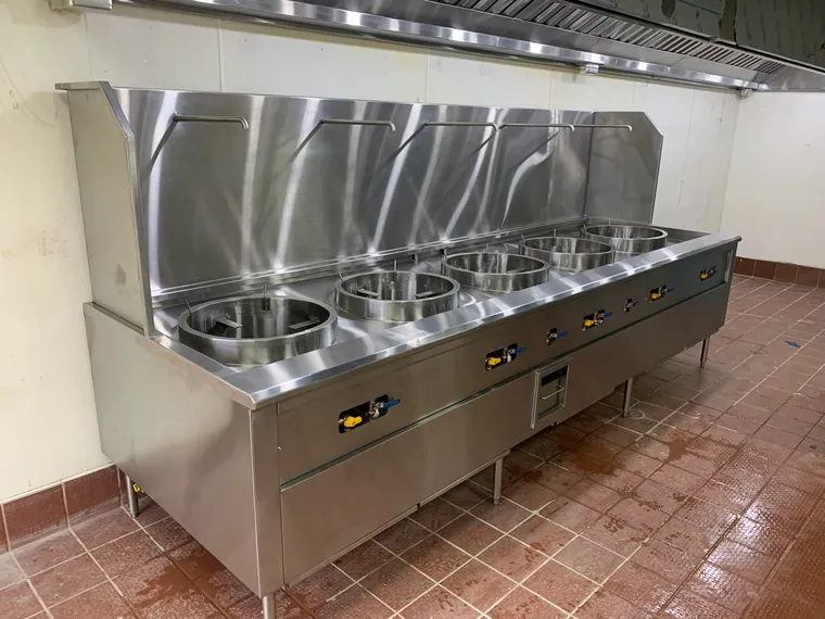 Línea de wok instalada con respaldo alto y campana de extracción