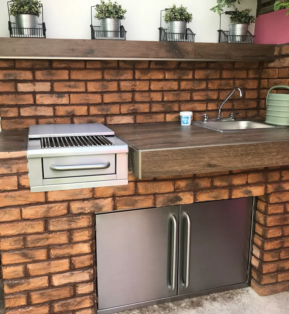 Área de asador empotrada en muro de ladrillo, con asador, tarja y puertas dobles de acero