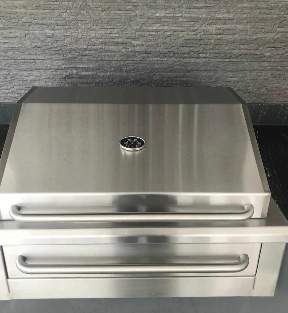 Asador empotrable de acero inoxidable con tapa y termómetro, integrado en encimera de piedra negra
